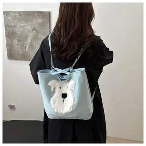 Close-up of a light blue tote bag with a white plush dog patch on a model's back