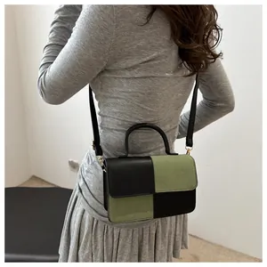 Dettaglio della borsa bicolore nero e verde oliva indossata da una modella elegante