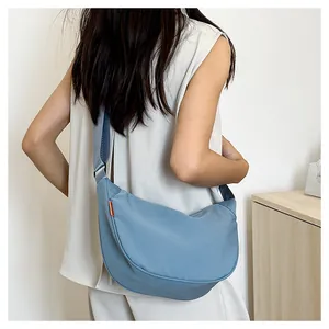 Detail view of the light blue crescent bag showing smooth nylon texture and orange logo tag