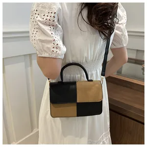 Dettaglio di una borsa bicolore minimalista in pelle nera e marrone con tracolla