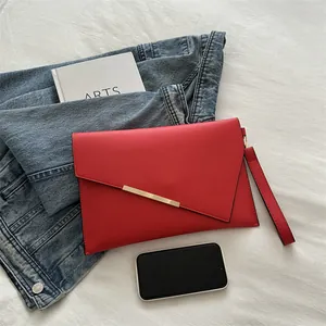 Fashionable red leather envelope clutch with asymmetric flap and golden metal trim