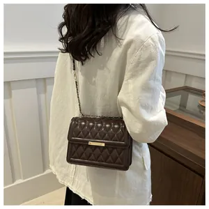 Detail of a chocolate brown quilted crossbody bag with gold metallic lock and chain strap