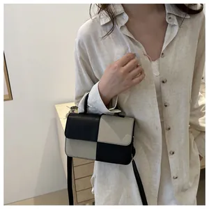 Dettaglio di una mini borsa quadrata in pelle bicolore con motivo a scacchi beige e nero