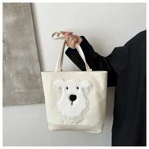 Detailed view of cream canvas tote bag with a 3D plush puppy patch and reinforced handles