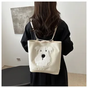 Detail view of cream tote bag with plush puppy embroidery on a model's back