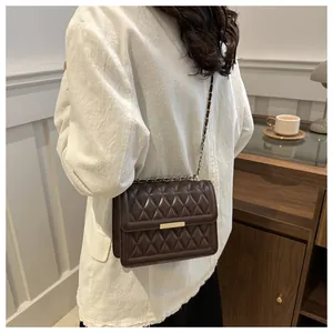 Detail of deep brown quilted crossbody bag with gold metal lock and chain strap