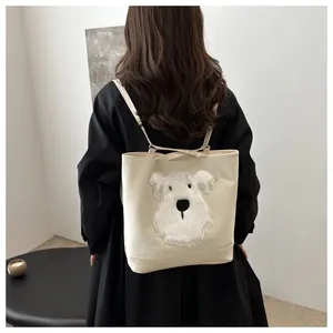 Detail of cream tote bag featuring a plush puppy embroidery shown on a model's shoulder