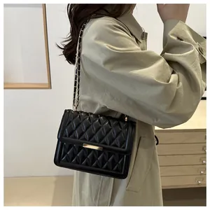 Detail of black quilted leather shoulder bag with gold metal buckle and chain strap