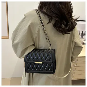 Close-up of quilted black leather crossbody bag with gold chain strap on model
