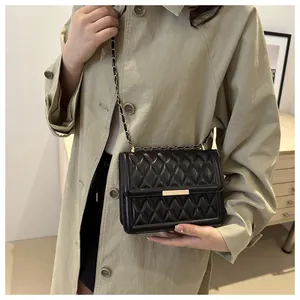 Close-up of black quilted leather crossbody bag with elegant gold metal chain and buckle