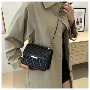 Detail of a black quilted leather crossbody bag featuring an elegant gold chain strap