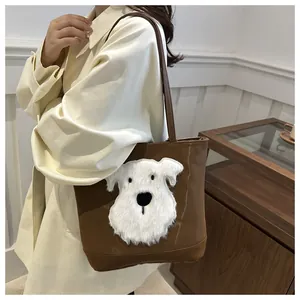 Close-up of brown leather tote bag featuring a white plush schnauzer dog patch detail