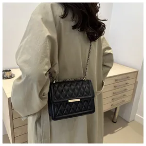 Detailed close-up of black quilted rhombus small square bag with golden metal buckle