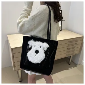 Detail view of large black tote bag featuring a plush puppy patch on the side