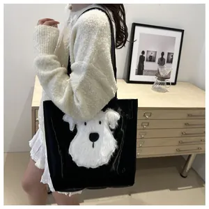 Detail of glossy black tote bag with white plush puppy patch and shoulder strap