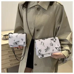 Détail de sacs à chaîne blancs à imprimé papillon en deux tailles portés par un mannequin