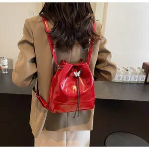 Detail of red patent leather bucket bag featuring a decorative silver butterfly charm