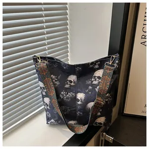 Detail of gothic tote bag featuring white skull print and ethnic woven shoulder strap