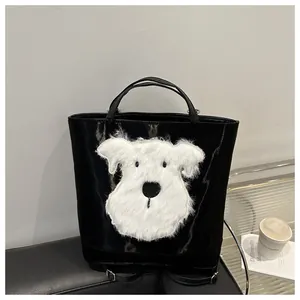Detail of black glossy tote bag featuring a white plush puppy patch in a modern setting
