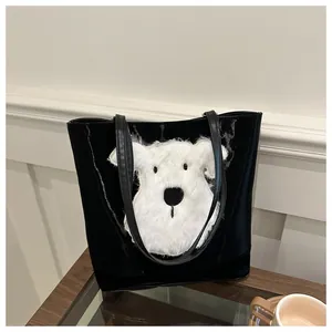 Detail of black tote bag with plush white puppy embroidery on a minimalist wooden table