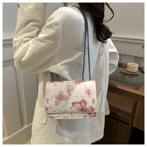 Détail du sac à bandoulière blanc avec imprimé papillon porté élégamment à l'épaule