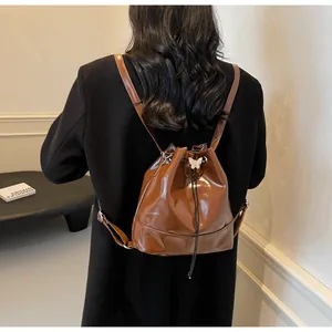 Detail of dark brown glossy PU leather bucket backpack with silver butterfly ornament