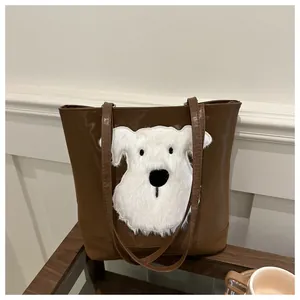 Close-up of a dark brown tote bag featuring a white plush puppy patch and leather texture