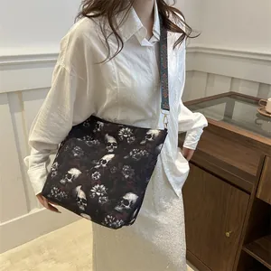 Large black tote bag with skull and floral prints and woven shoulder strap