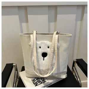Detail of white tote bag featuring plush bear embroidery on a smooth synthetic leather surface