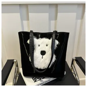 Detail of black glossy faux leather tote bag with white plush dog applique decoration