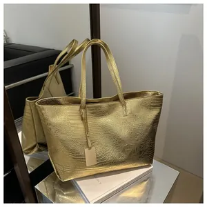 Detailed close-up showing glossy crocodile texture on a large golden tote bag