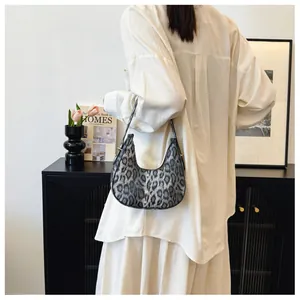 Détail du sac croissant à imprimé léopard sombre avec boucle métallique sur la bandoulière
