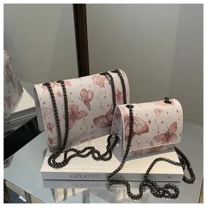 Détail de deux sacs blancs à imprimé papillon rose avec bandoulières en chaîne métal