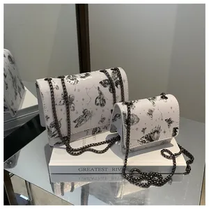 Détail de sacs à imprimé papillon avec chaînes métalliques et motifs étoilés
