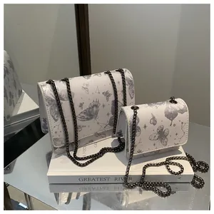 Vue détaillée de deux sacs à bandoulière blancs à imprimé papillon en deux tailles