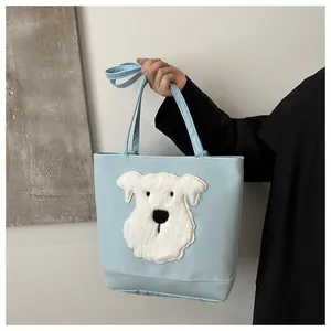 Detail of light blue tote bag with white plush puppy patch and shoulder strap design