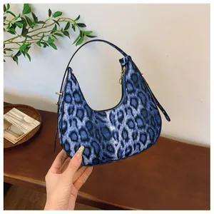 Détail du sac croissant imprimé léopard bleu avec poignée noire et fermeture dorée