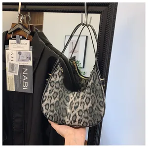 Gros plan sur le sac hobo à imprimé léopard gris avec des rivets dorés sur le côté
