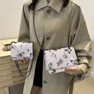 Sac à chaîne blanc imprimé papillon en deux tailles porté avec un trench-coat