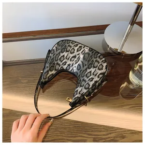 Vue détaillée du sac en croissant imprimé léopard posé sur une table en bois élégante