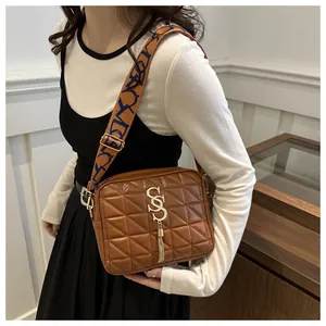 Detail of brown quilted crossbody bag with golden logo and blue patterned wide strap