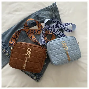 Detail of quilted crossbody bags in brown and blue with jacquard woven guitar straps