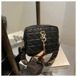 Detail of black quilted shoulder bag featuring gold hardware and stylish tassel charm