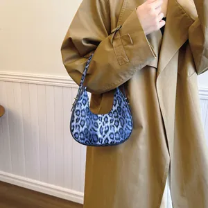 Sac à main croissant à imprimé léopard bleu porté avec un trench-coat chic