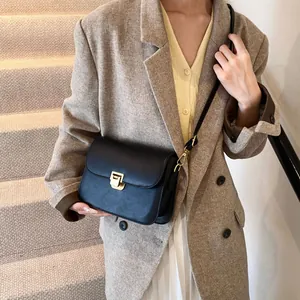 Classic black leather crossbody bag with gold lock buckle worn on a shoulder