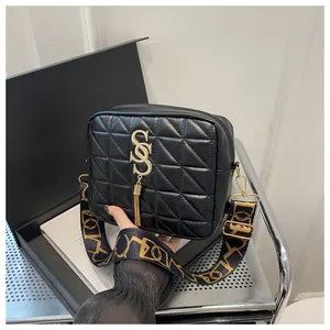Detail of black quilted shoulder bag featuring gold hardware and wide jacquard strap