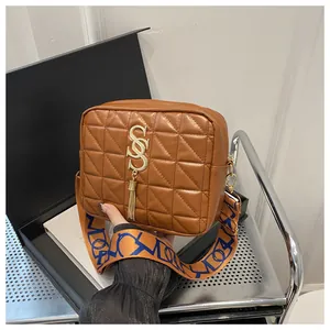 Close-up of caramel quilted crossbody bag with golden tassel and patterned strap