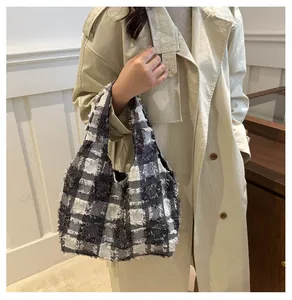 Détail du sac cabas à carreaux avec texture frangée sur un trench-coat beige d'automne