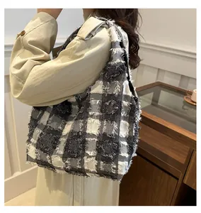 Détail d'un grand sac cabas à carreaux avec bords effilochés et franges décoratives