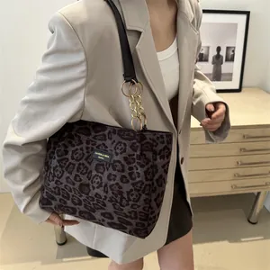 Leopard print tote bag with black leather shoulder strap and golden metal chain details